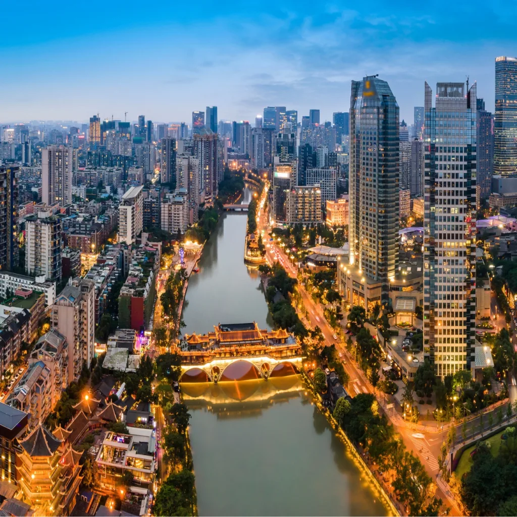 Vista aérea de Chengdú al anochecer con el puente Anshun iluminado sobre el río