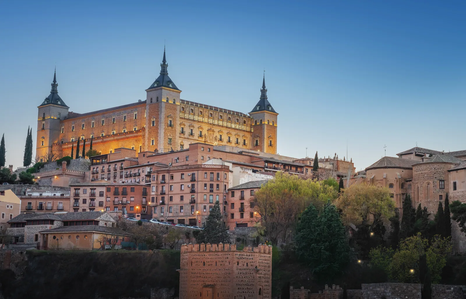 El Alcázar de Toledo, un edificio cuadrado de piedra con cuatro torres, en lo alto del casco histórico
