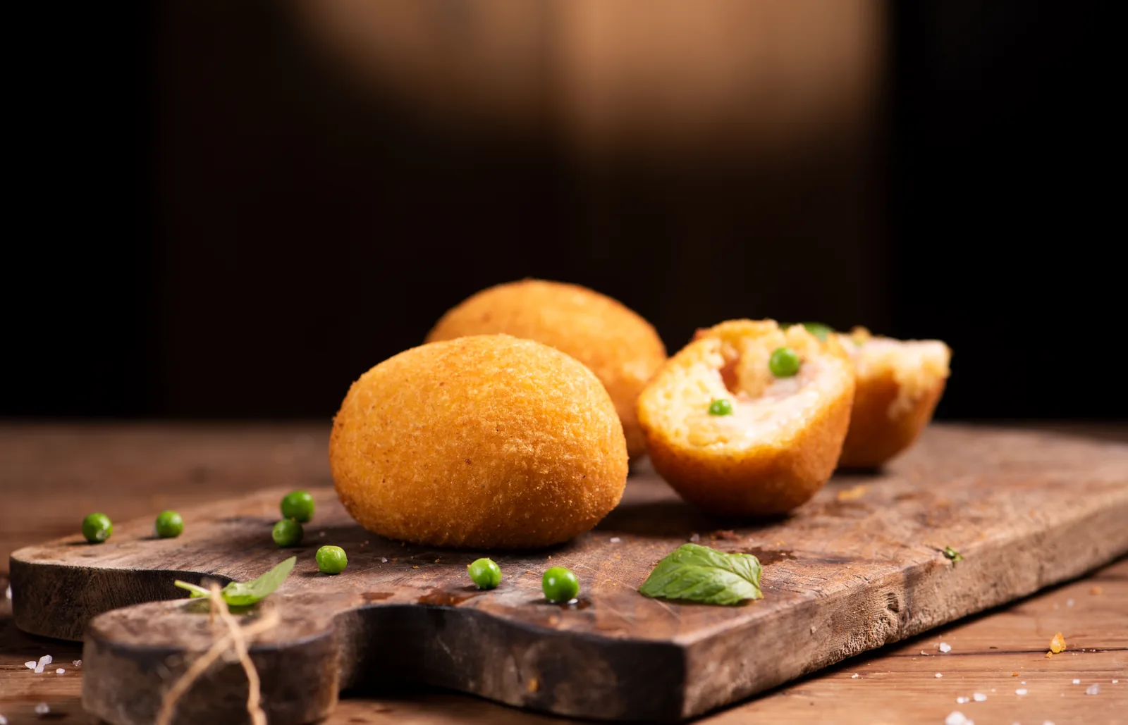 Arancine sicilianas, bolas de arroz rebozadas y fritas, una de ellas abierta por la mitad