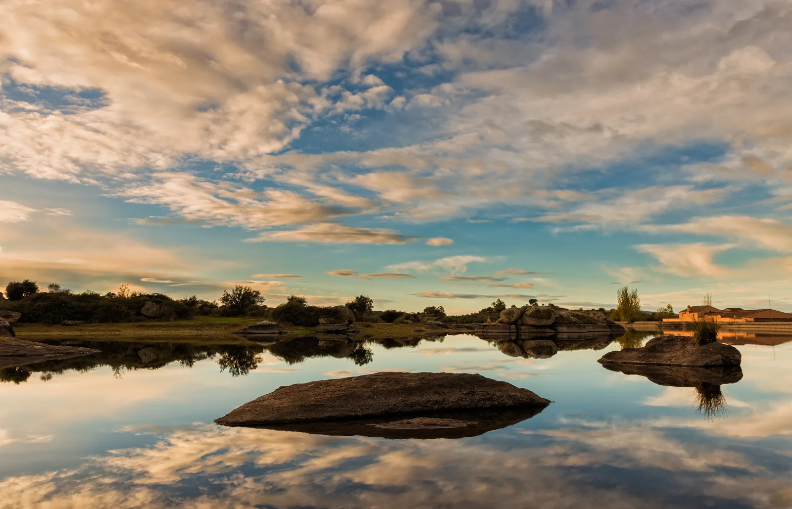 Bolos de granito reflejados en una charca de Los Barruecos, en Malpartida de Cáceres, al atardecer