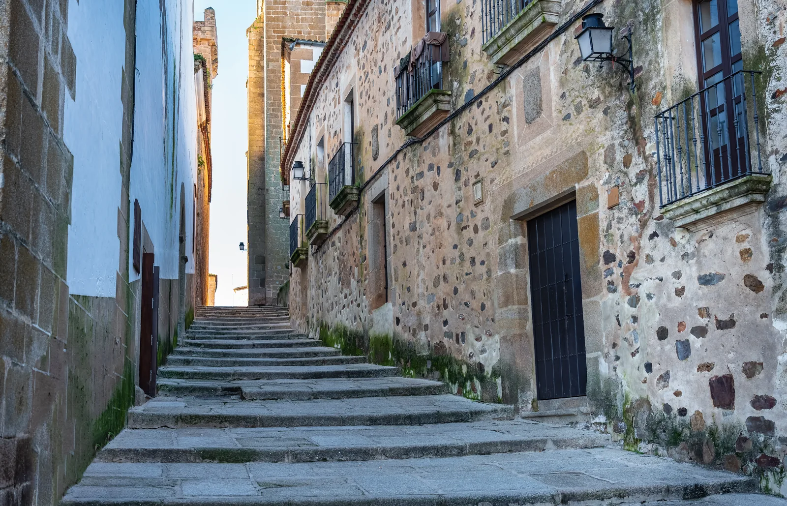 Calle empedrada con escalones entre muros de piedra en la Ciudad Monumental de Cáceres