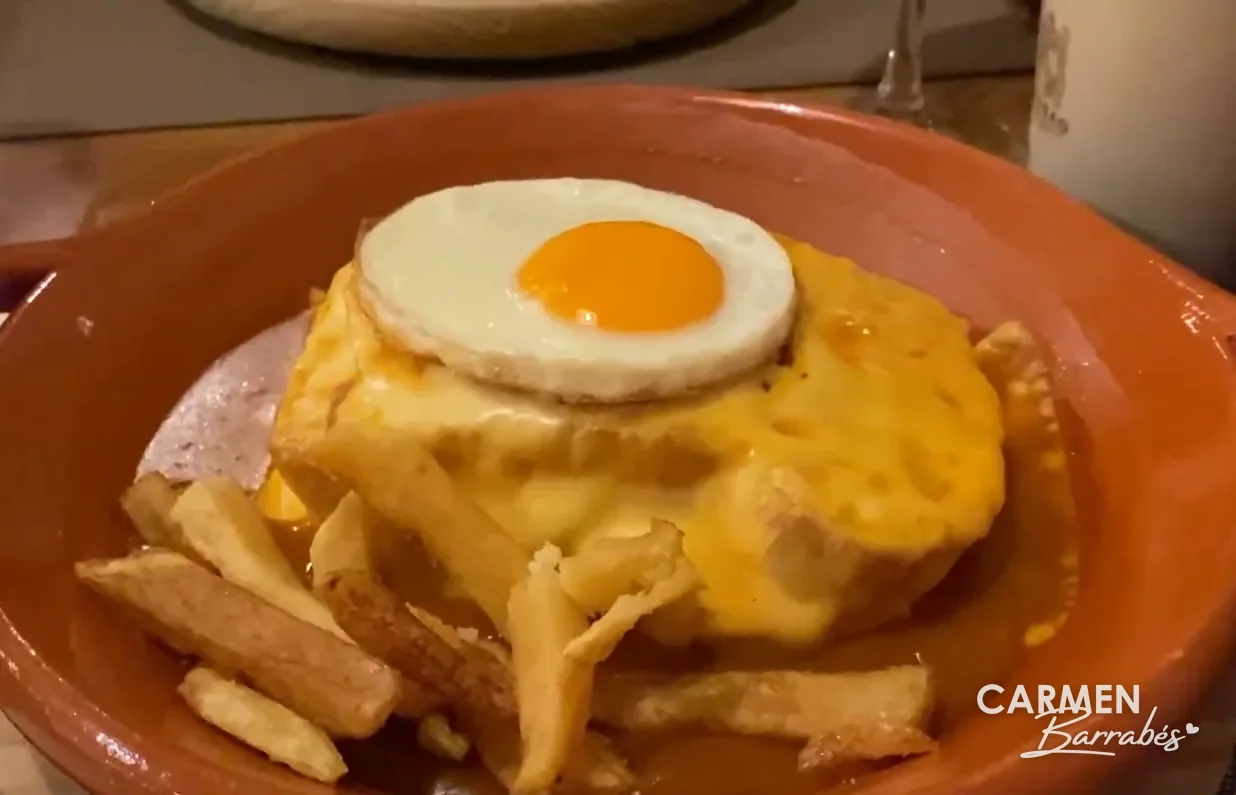 Francesinha con huevo frito, salsa y patatas fritas en una cazuela de barro