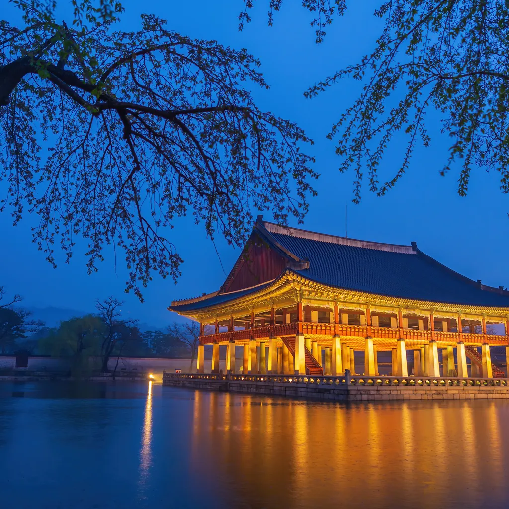 El pabellón Gyeonghoeru del palacio Gyeongbokgung iluminado de noche, reflejado en el estanque