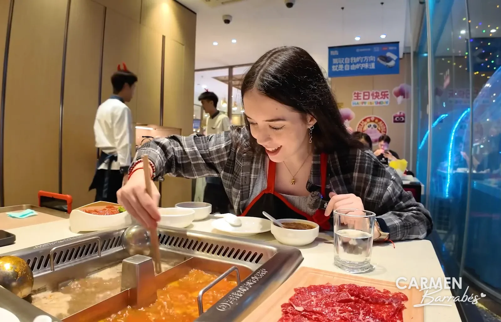 Carmen Barrabés sonriendo mientras cocina en la olla doble de hotpot de un Haidilao de Shanghái