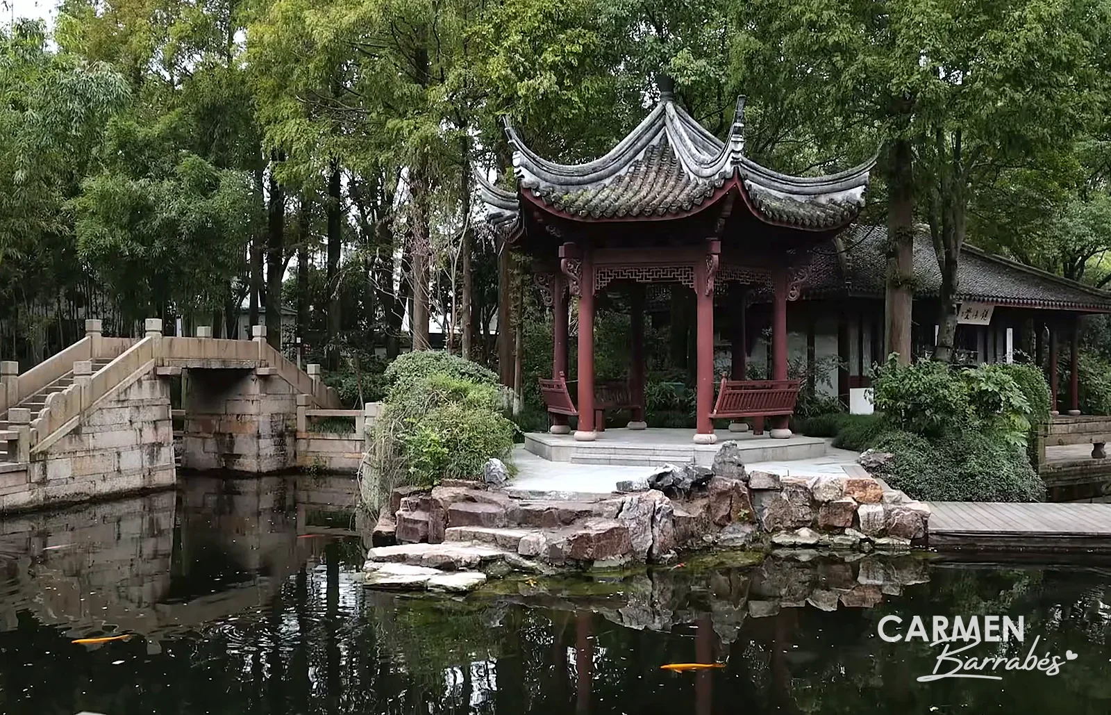 Pabellón rojo sobre el estanque del jardín Kezhi de Zhujiajiao, con un puente de piedra y rocalla