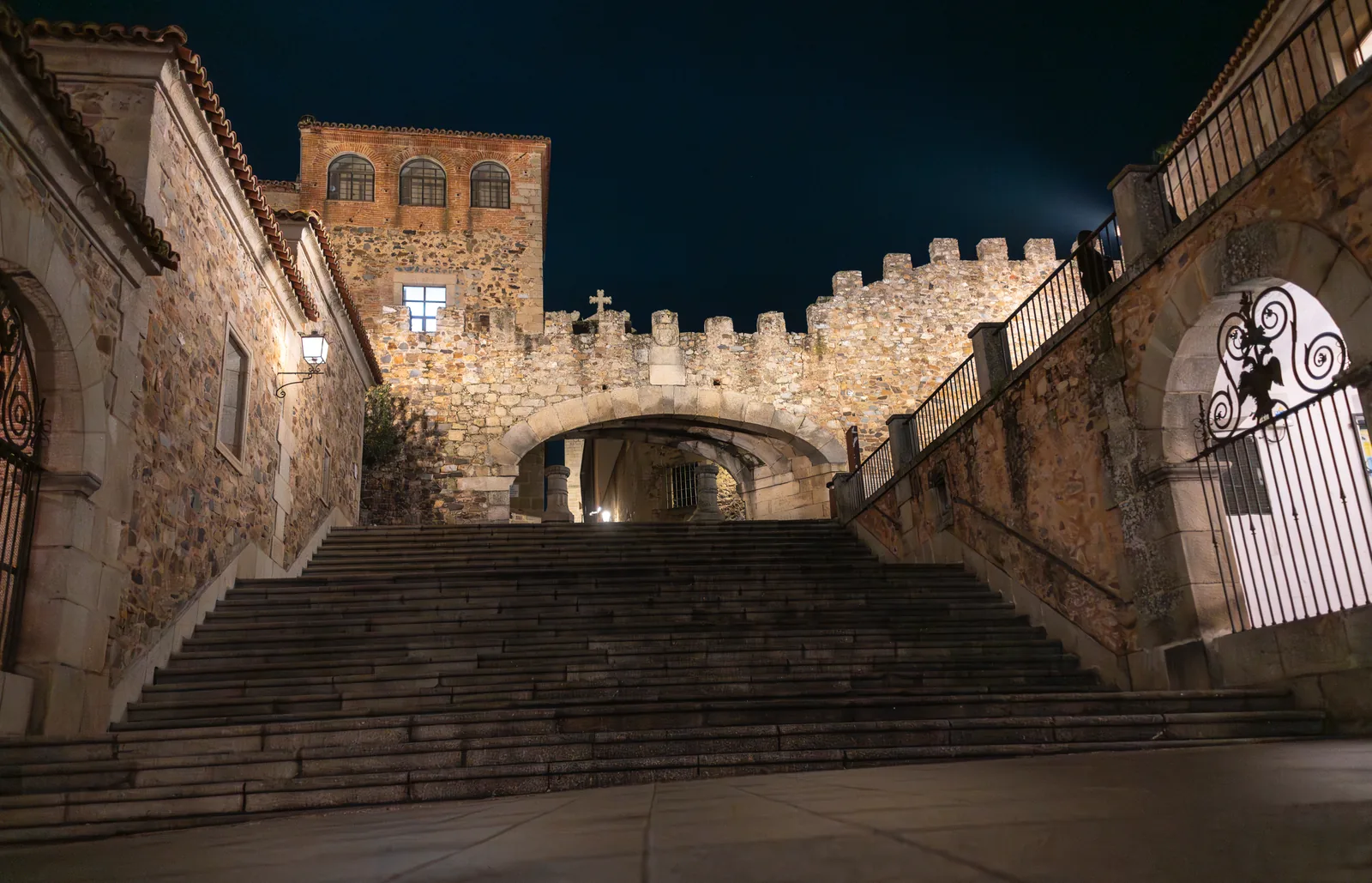 El Arco de la Estrella de Cáceres iluminado de noche, en lo alto de la escalinata que sube desde la Plaza Mayor