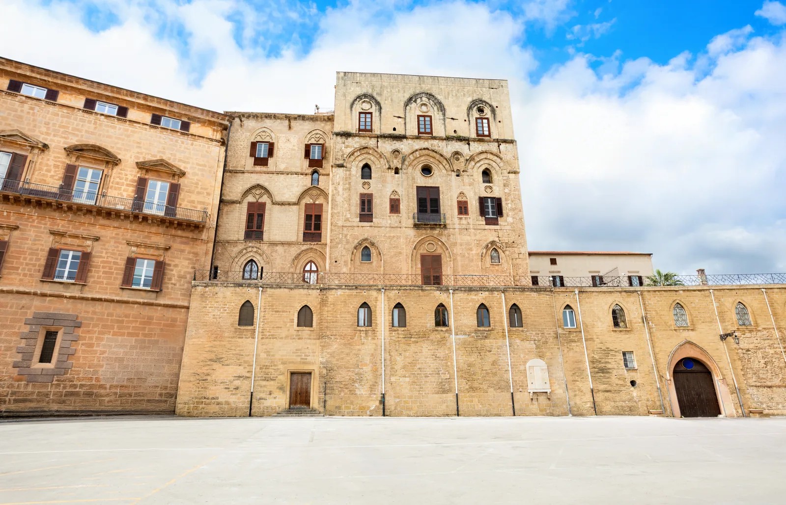 La fachada del Palacio de los Normandos de Palermo, de piedra dorada, con la plaza vacía delante