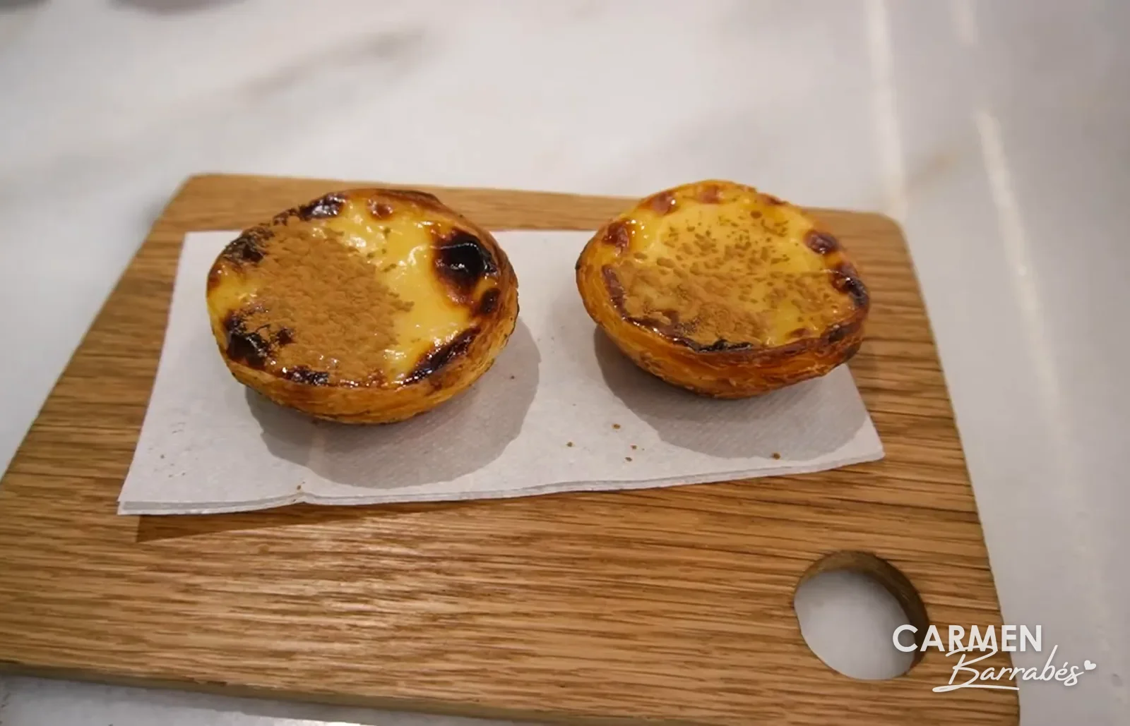 Dos pastéis de nata recién hechos de Manteigaria sobre una tabla de madera