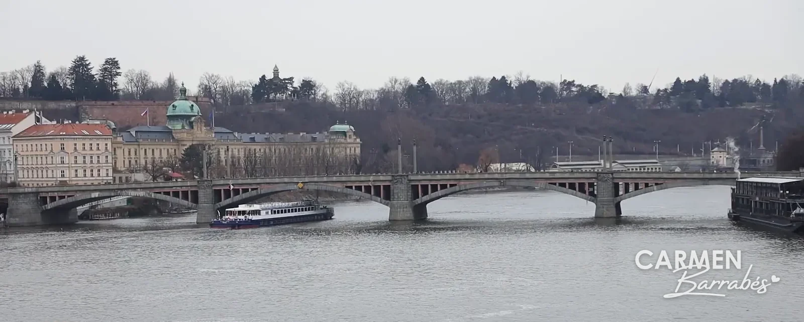 Un barco turístico por el río Moldava, visto desde el Puente de Carlos un día nublado