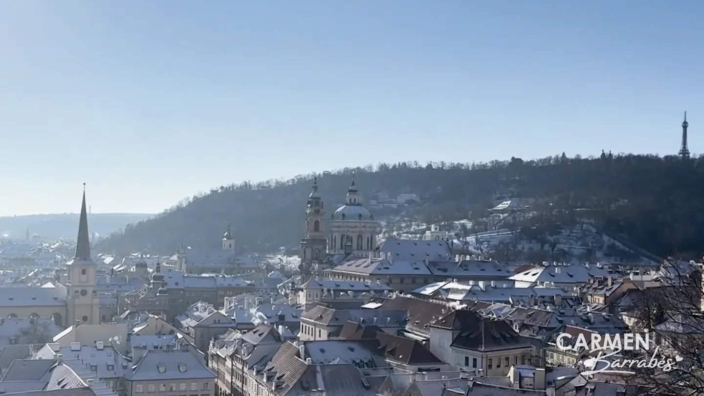 Tejados nevados de Malá Strana con la cúpula y el campanario de San Nicolás, y la Torre Petřín en lo alto de la colina