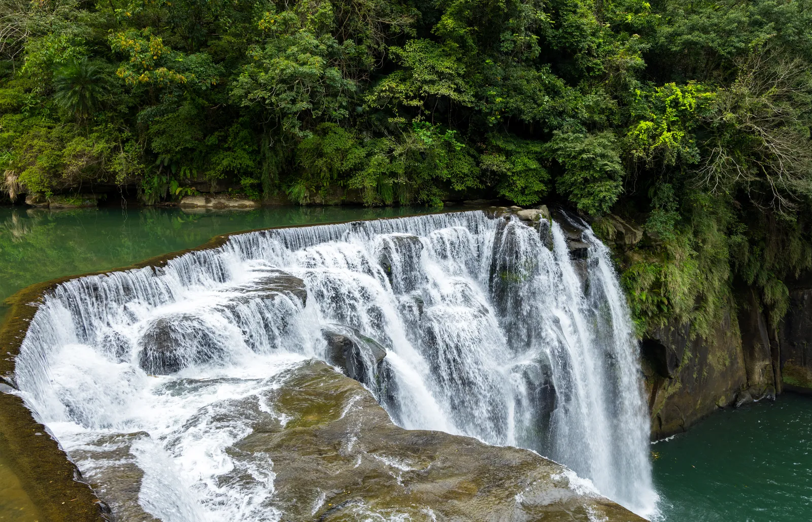 Cascada de Shifen cayendo sobre las rocas a una poza verde, rodeada de selva