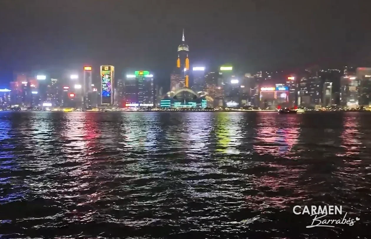 Rascacielos de la isla de Hong Kong iluminados de noche desde el paseo de Tsim Sha Tsui, reflejados en la bahía Victoria