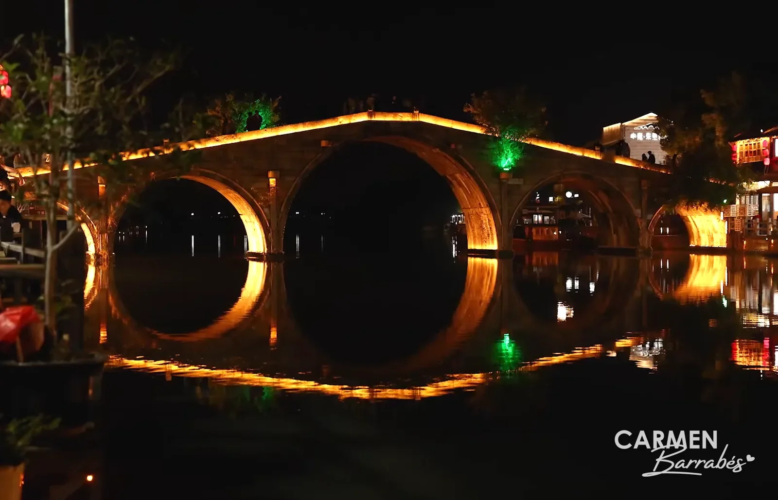 Puente Fangsheng de Zhujiajiao iluminado de noche y su reflejo en el canal